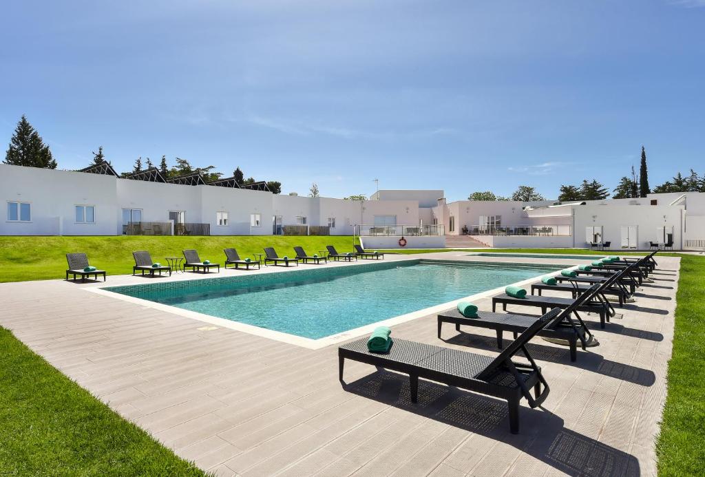 a pool with chaises and chairs next to a building at Serpa Hotel in Serpa