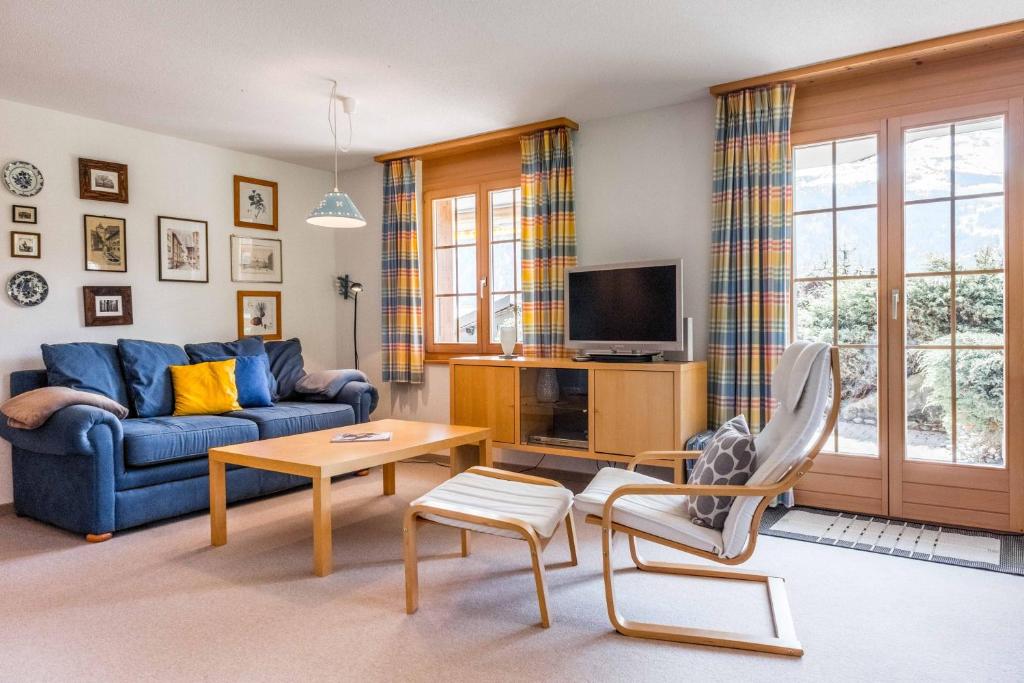 a living room with a blue couch and a table at Apartment Hori - GRIWA RENT AG in Grindelwald