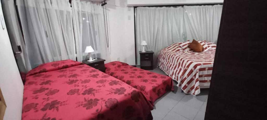 - une chambre avec 2 lits et des draps rouges dans l'établissement Apartamentos Willy - en Zona Residencial con Estacionamiento, à Mendoza