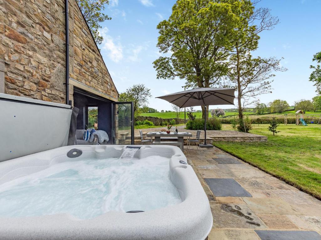 a bath tub in a yard with an umbrella at Holme House in Eldroth