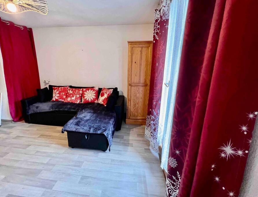 a living room with a couch and red curtains at Studio à Praz-sur-Arly in Praz-sur-Arly