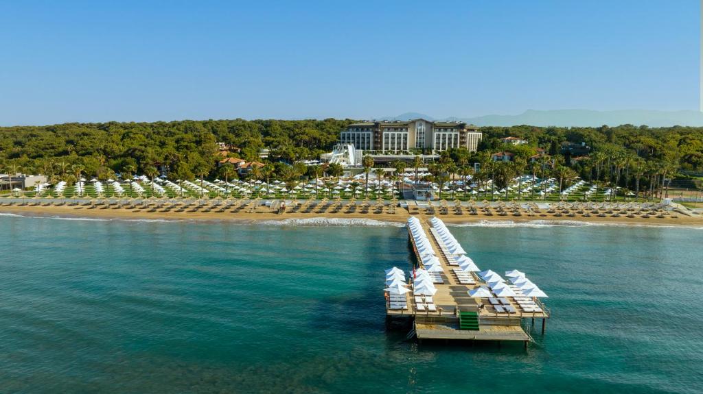 een steiger met witte stoelen en een strand bij Voyage Sorgun Hotel in Side