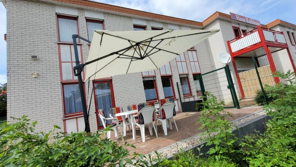 a patio with chairs and an umbrella in front of a building at Sachsentraum in Reichenbach im Vogtland