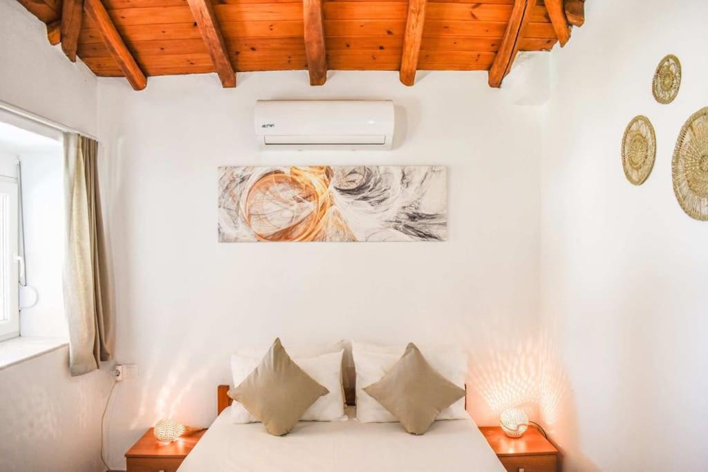 a bedroom with a bed with white sheets and pillows at HUT HOUSE Εξοχικό στην παραλία Μ. Άμμος in Skiathos