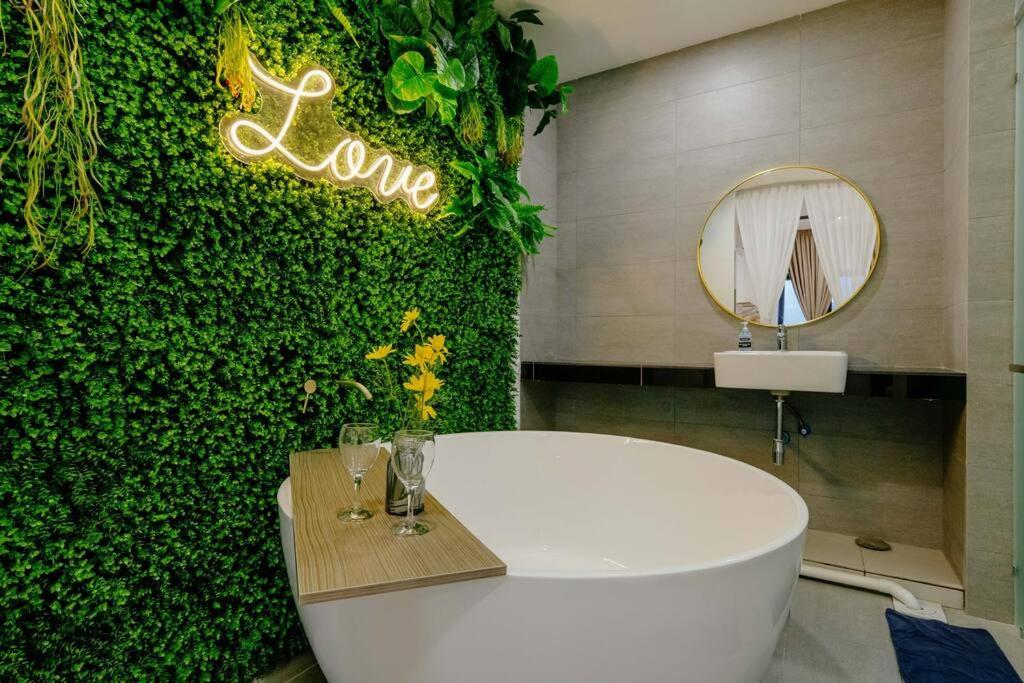 a bathroom with a white tub in front of a green wall at The Pano Residence Jalan Ipoh Insta-worthy Bath Tub Studio 浴缸MRT in Kuala Lumpur