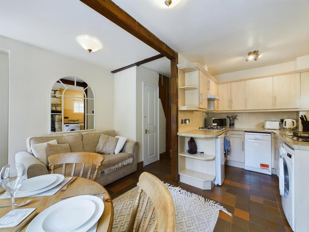 cocina y sala de estar con sofá y mesa en Romantic Cottage Cotswolds Parking Wi-Fi en Winchcombe