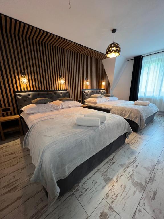 two beds in a large room with wooden walls at Ostoya Twoya in Poronin