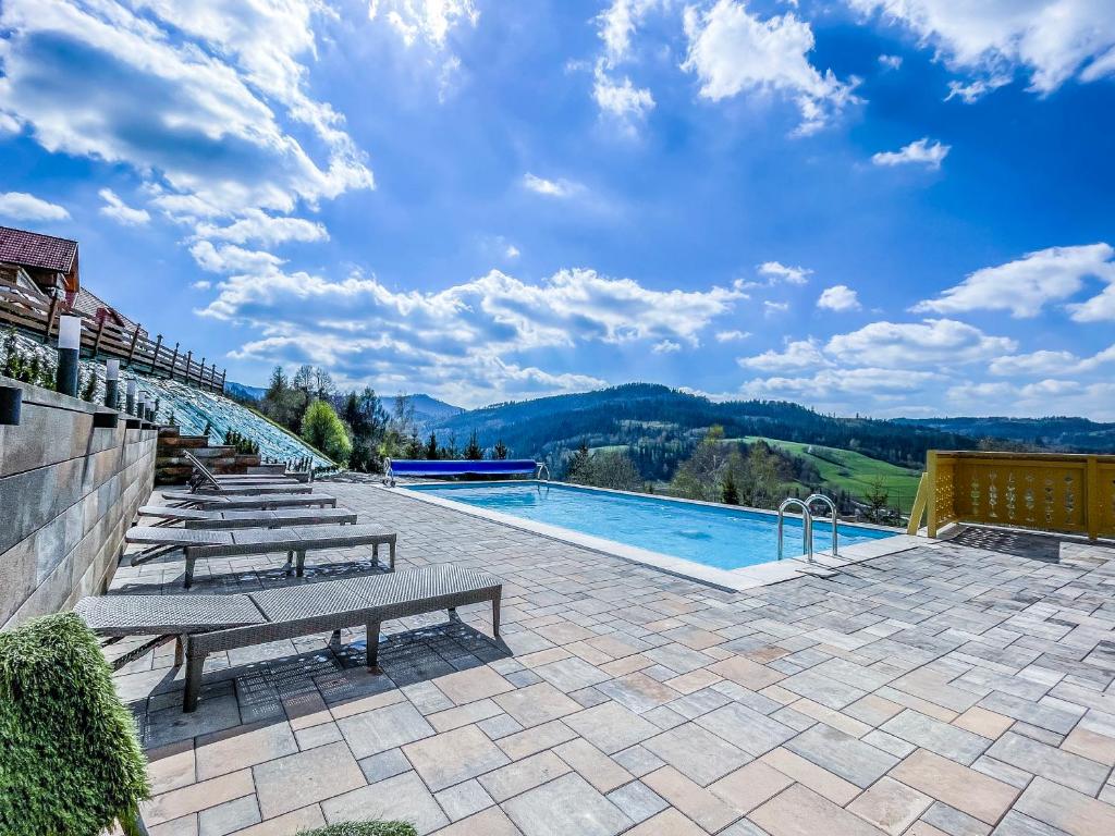 a swimming pool with benches and a view of the mountains at Karolowy Dwór in Wisła
