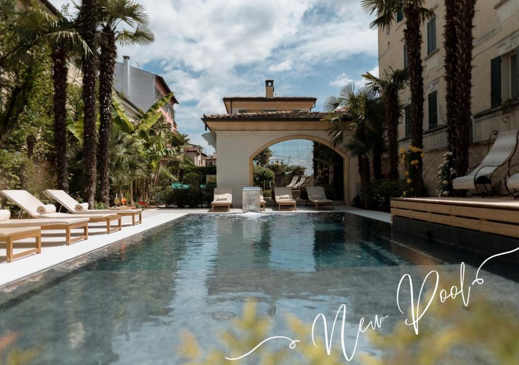 a large swimming pool with chairs and a building at Classique in Lazise