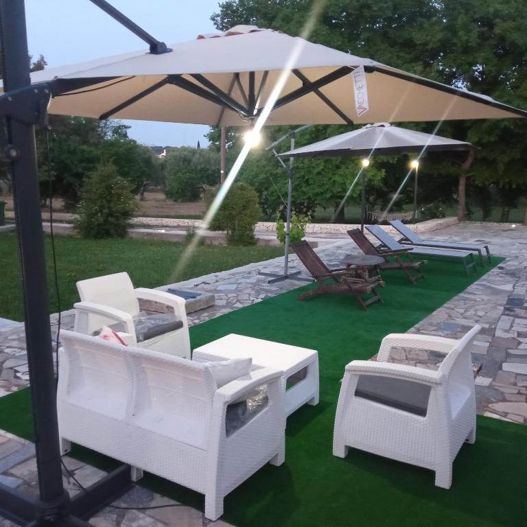 grupa krzeseł i parasol na trawniku w obiekcie Villa Il Leccio - Trulli w mieście Cisternino