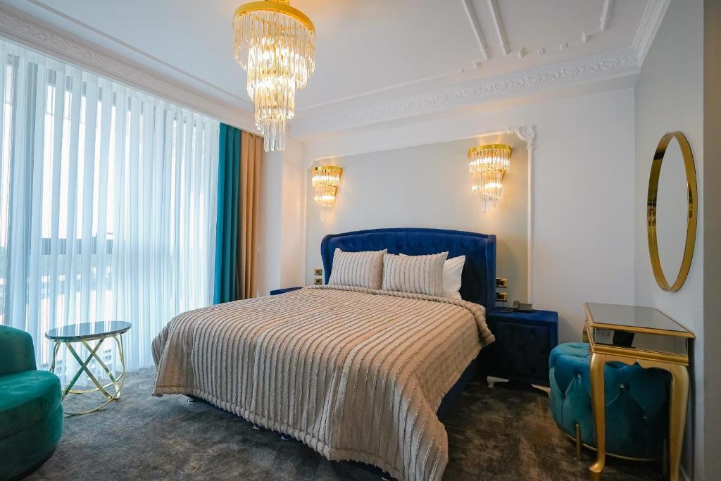 a bedroom with a bed and a blue chair at W Regal Boutique Hotel&Spa in Mamaia