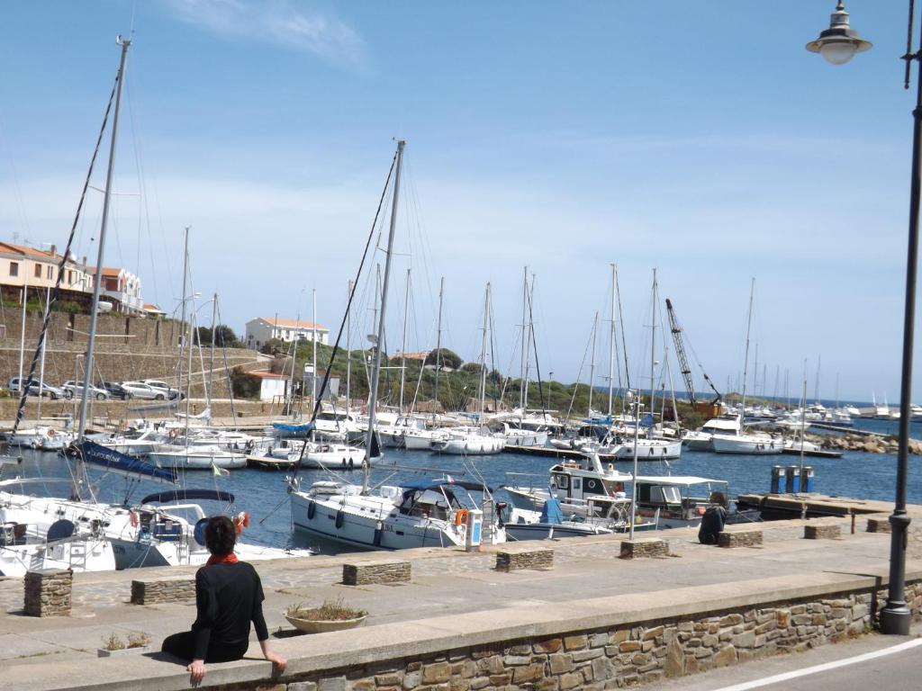 a woman sitting on a wall looking at boats in the water at B&B Il Gatto Pescatore in Stintino