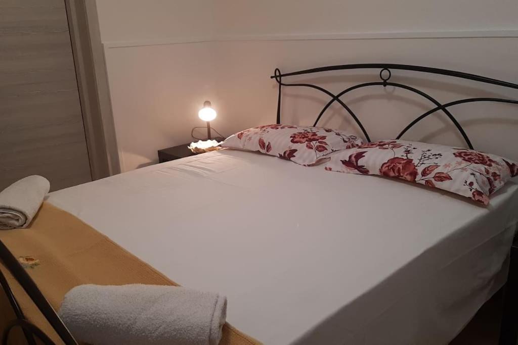 un letto bianco con cuscini rossi e bianchi di Aledò, casa vacanze a Casalabate