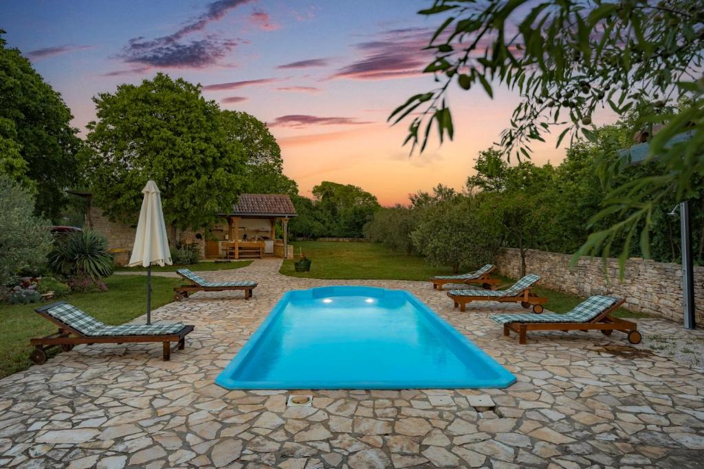 a swimming pool with benches and an umbrella and a table at Villa Daja - Adriatic Luxury Villas in Oklaj