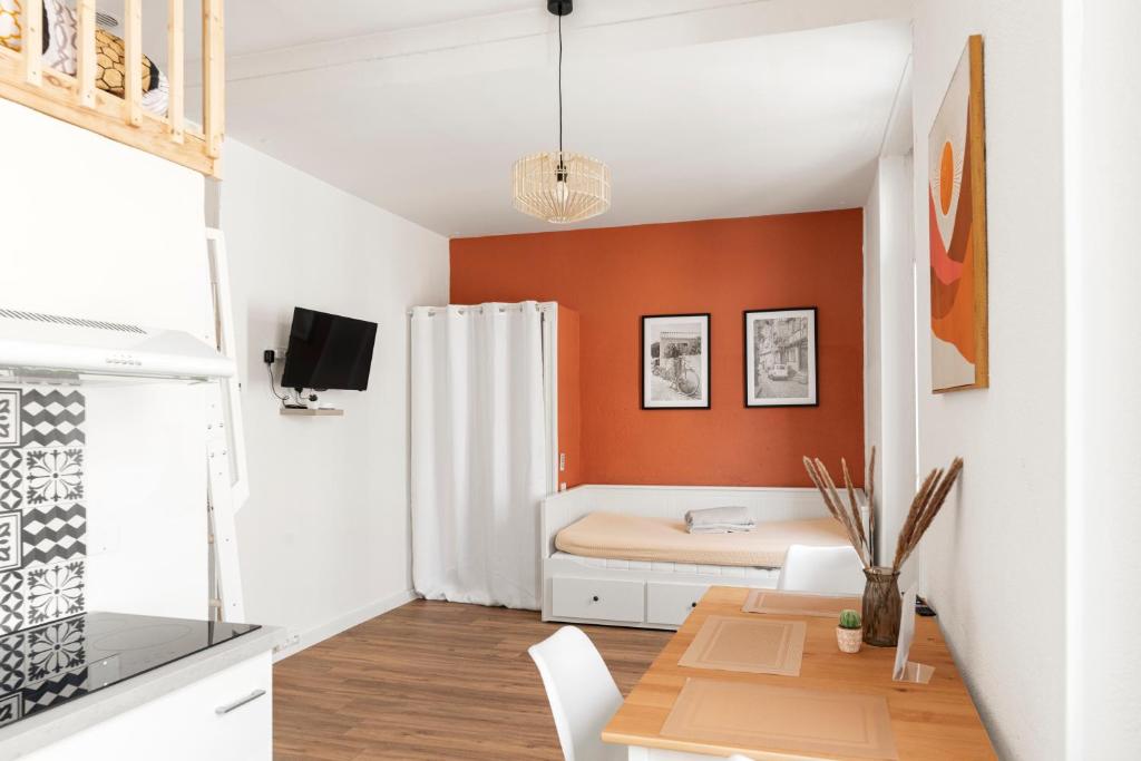 Ce petit appartement est doté de murs orange et d'une salle à manger. dans l'établissement MontSéjour - Studio Climatisé entre Gare & Cité, à Carcassonne