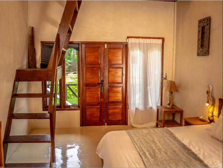 ein Schlafzimmer mit einer Leiter, einem Bett und einem Fenster in der Unterkunft Dylan’s Retreat in Lasikin
