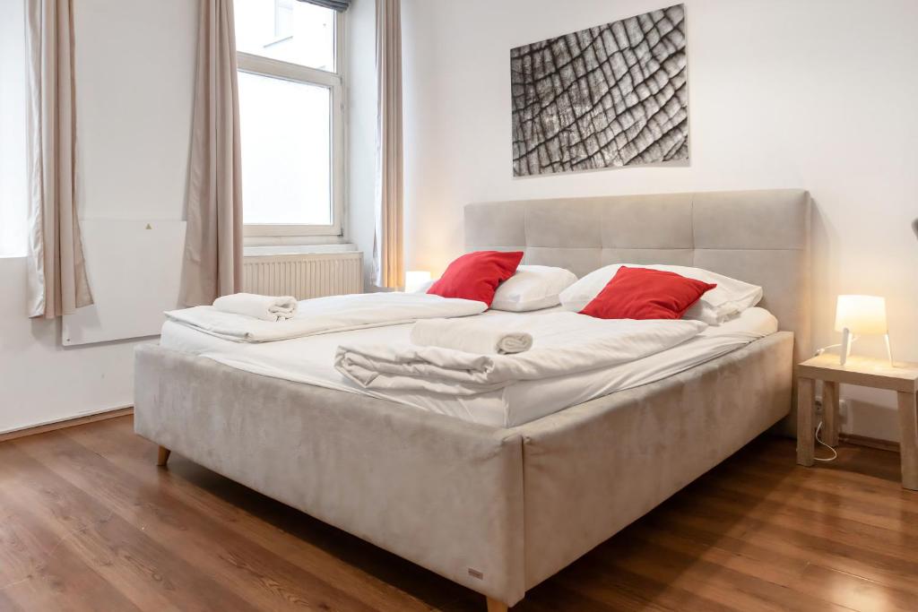 a large white bed with red pillows in a room at Modern 1BR Apart- Suitable for Longstays in Vienna