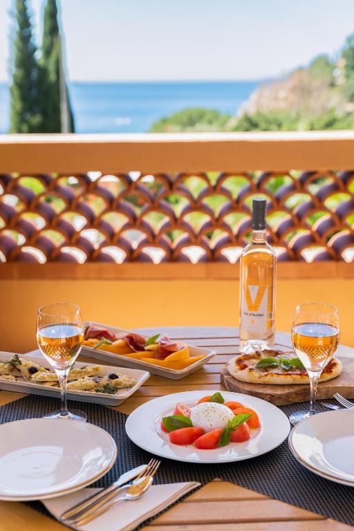 a table with plates of food and a bottle of wine at Les Terrasses du Bailli in Rayol-Canadel-sur-Mer