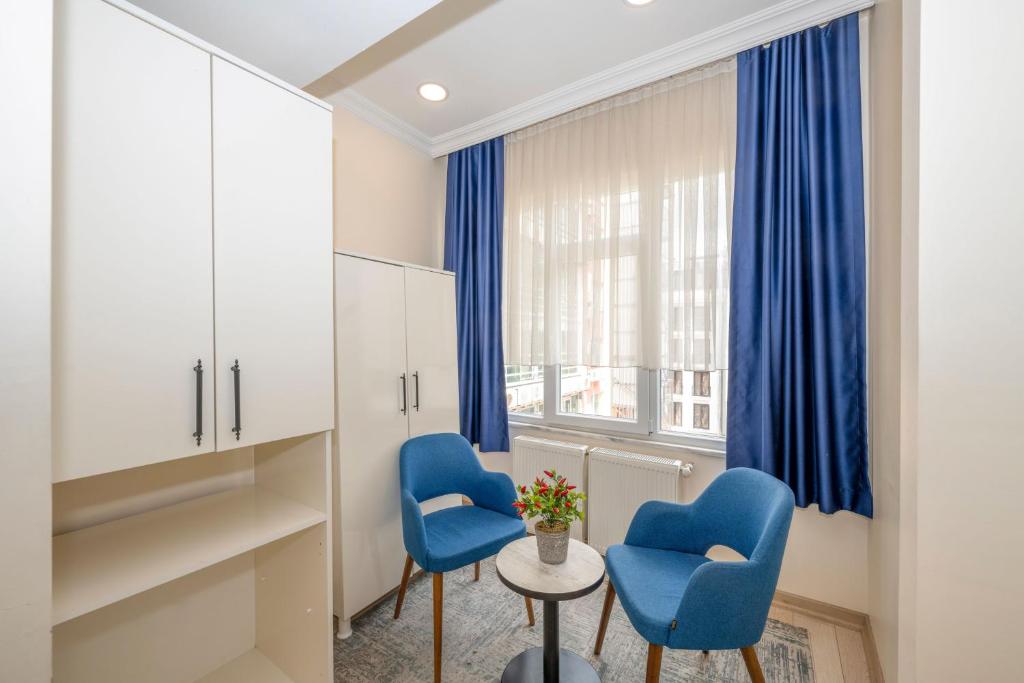 een kamer met 2 blauwe stoelen en een raam bij Hotel Grand İstanbul in Istanbul