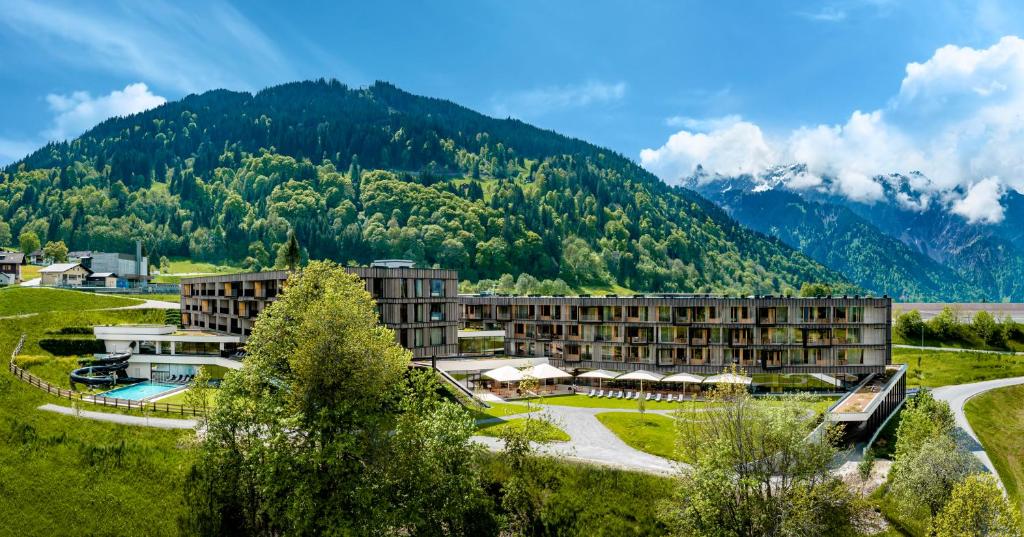 a resort with a mountain in the background at Falkensteiner Family Hotel Montafon - The Leading Hotels of the World in Schruns