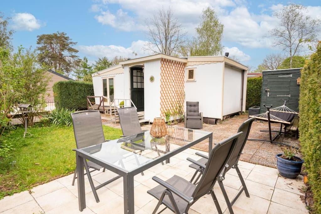 a patio with a table and chairs in a yard at Knus huisje op kindvriendelijk park met zwembad in Otterlo