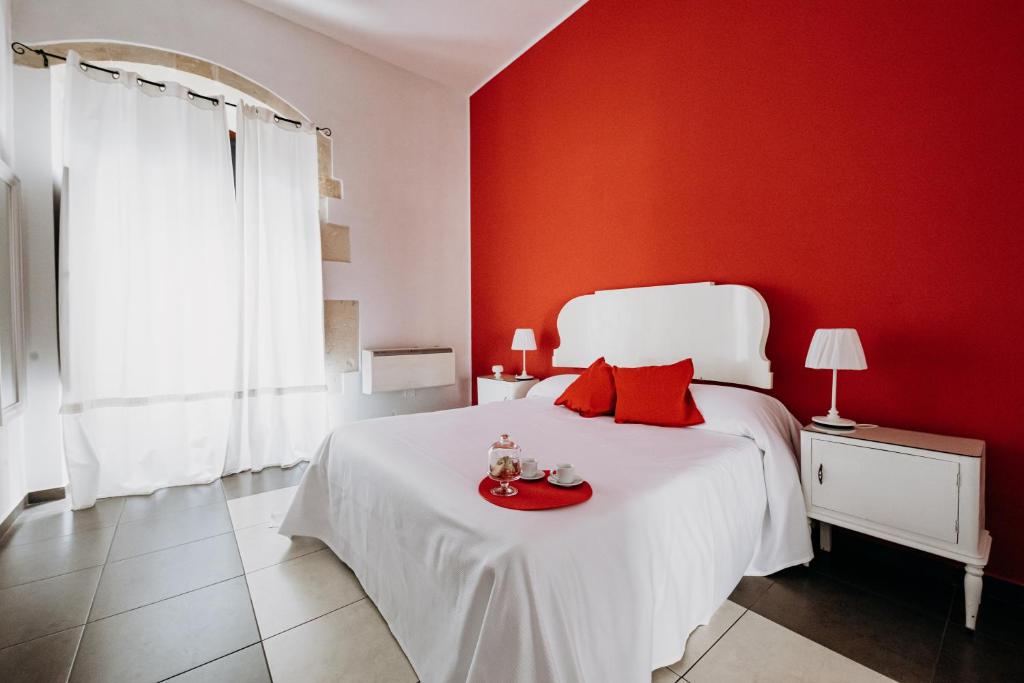 Dormitorio rojo con cama blanca y pared roja en Kyanos Residence, en Siracusa