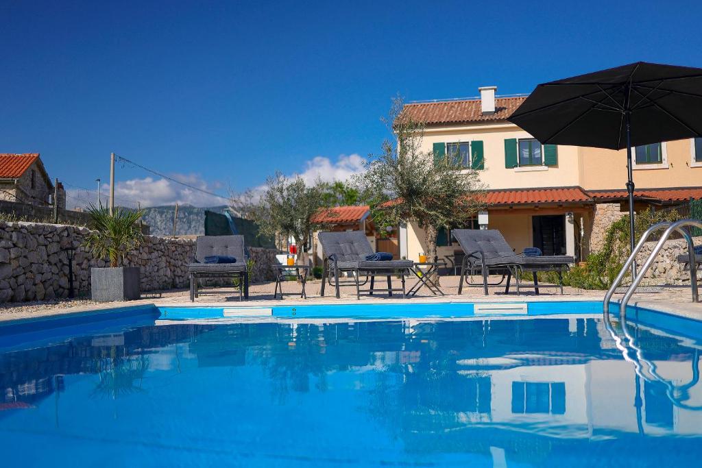 una casa y una piscina con sombrilla y sillas en Villa Niko Your vacation starts here, en Rudine