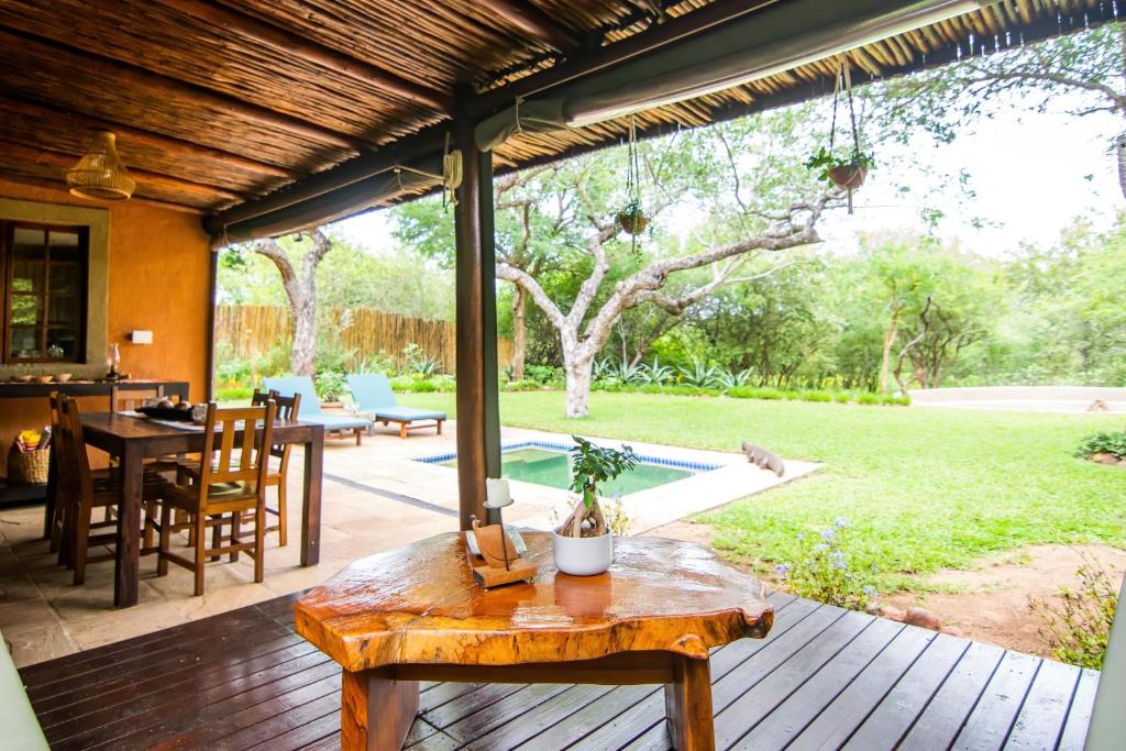 een veranda met een houten tafel en een patio bij Braai Safaris Lodge in Hoedspruit