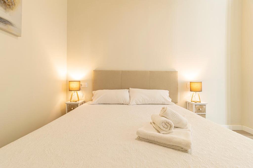 Un dormitorio con una cama blanca con toallas. en Top & Chic Albarizuela Suites - Apartamentos Jerez, en Jerez de la Frontera