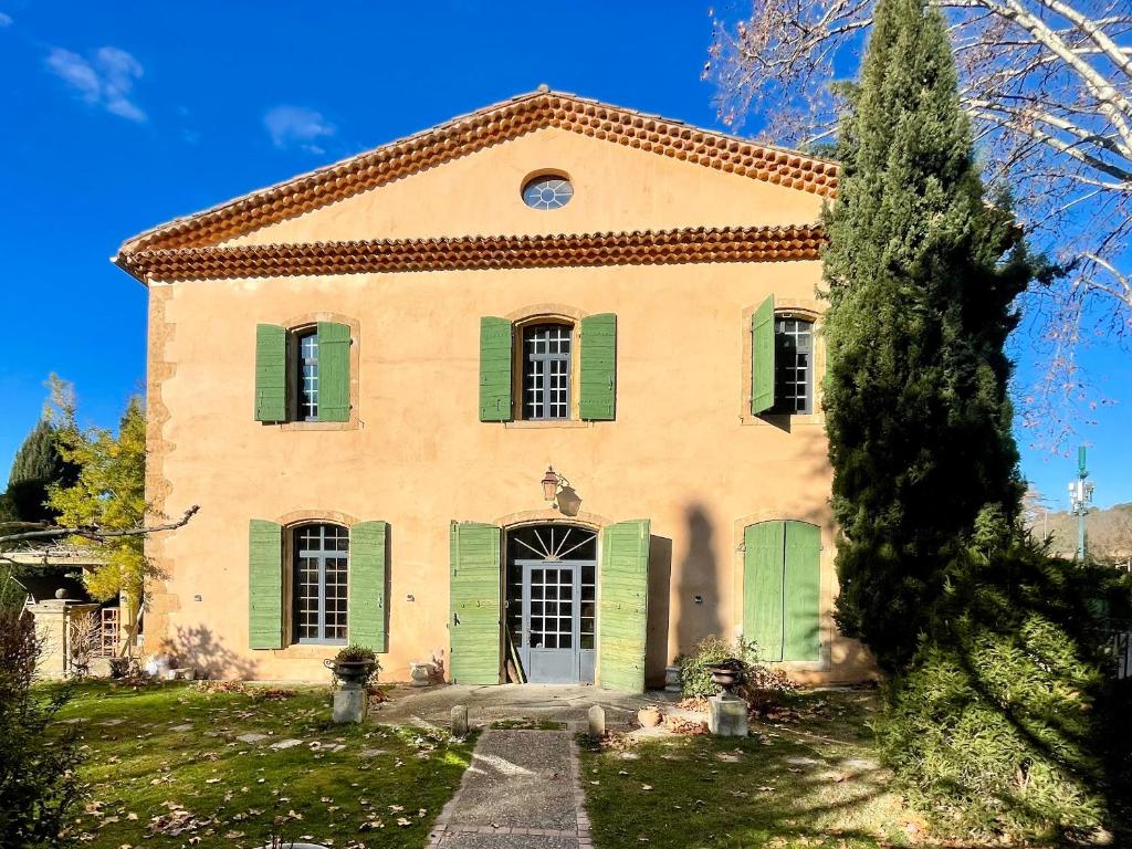 an old house with green shutters and a tree at Domaine Bellefontaine in Aix-en-Provence