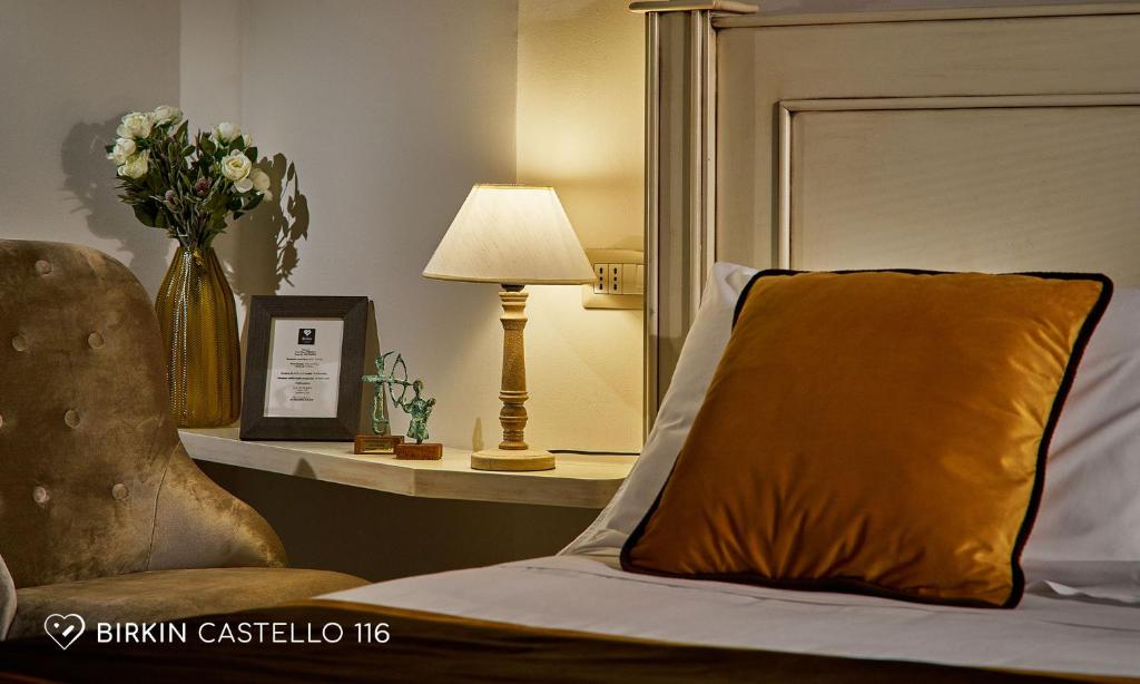 a bed with a pillow and a table with a lamp at Albergo Diffuso Birkin Castello in Cagliari