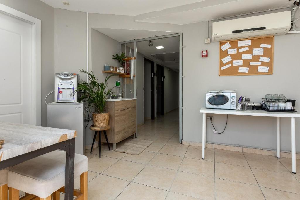 eine Küche mit einem Tisch und einer Theke mit einer Mikrowelle in der Unterkunft Little Prince Hostel-5 Min Walk To The Beach in Eilat