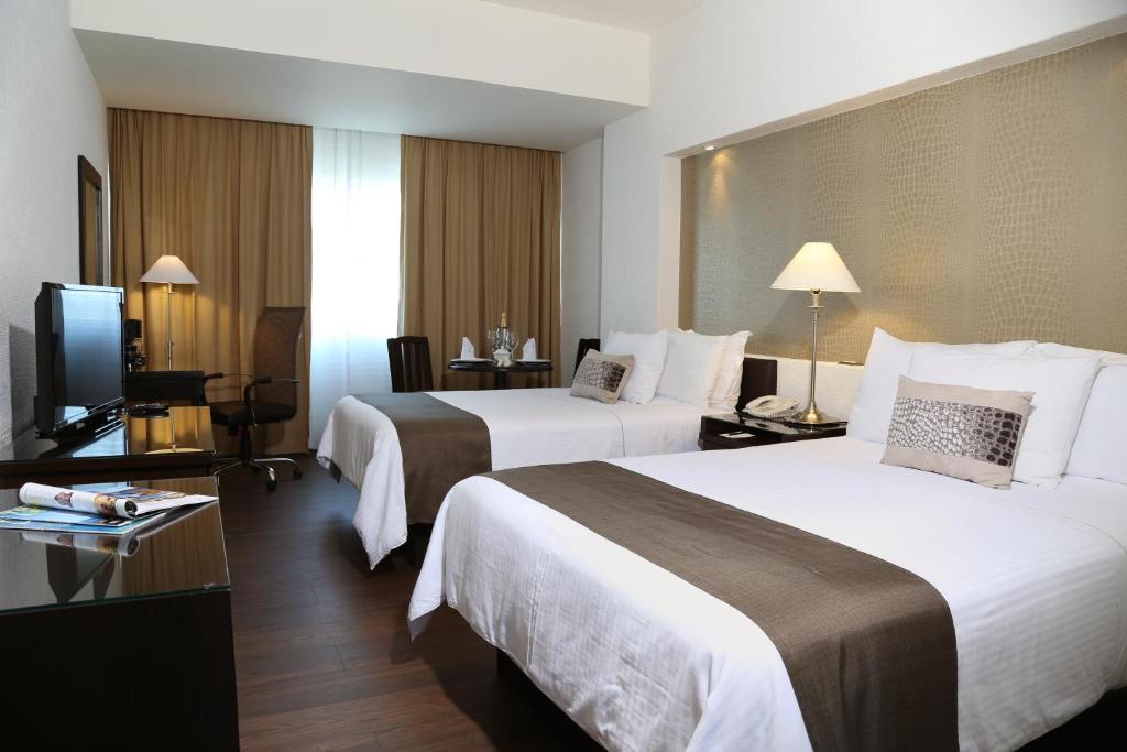 een hotelkamer met 2 bedden en een televisie bij Mesón Ejecutivo Guadalajara Minerva - Av México in Guadalajara