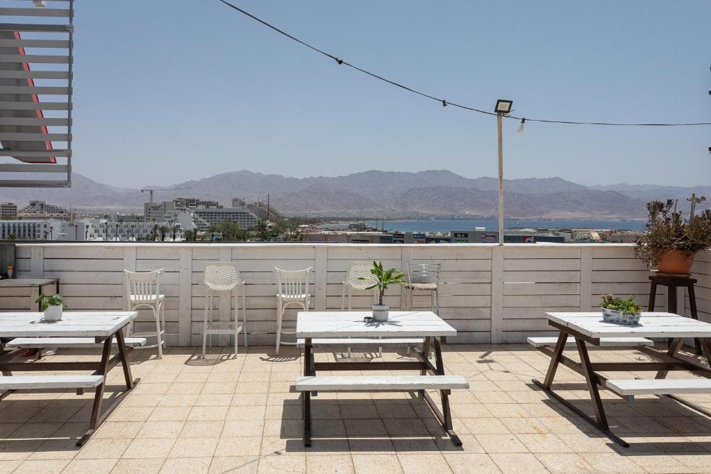 eine Terrasse mit Tischen und Stühlen auf dem Dach in der Unterkunft Little Prince Hostel-5 Min Walk To The Beach in Eilat