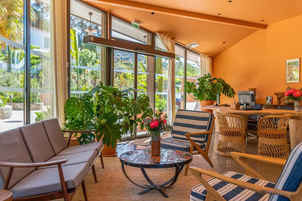a living room with chairs and tables and windows at Les Terrasses du Bailli in Rayol-Canadel-sur-Mer