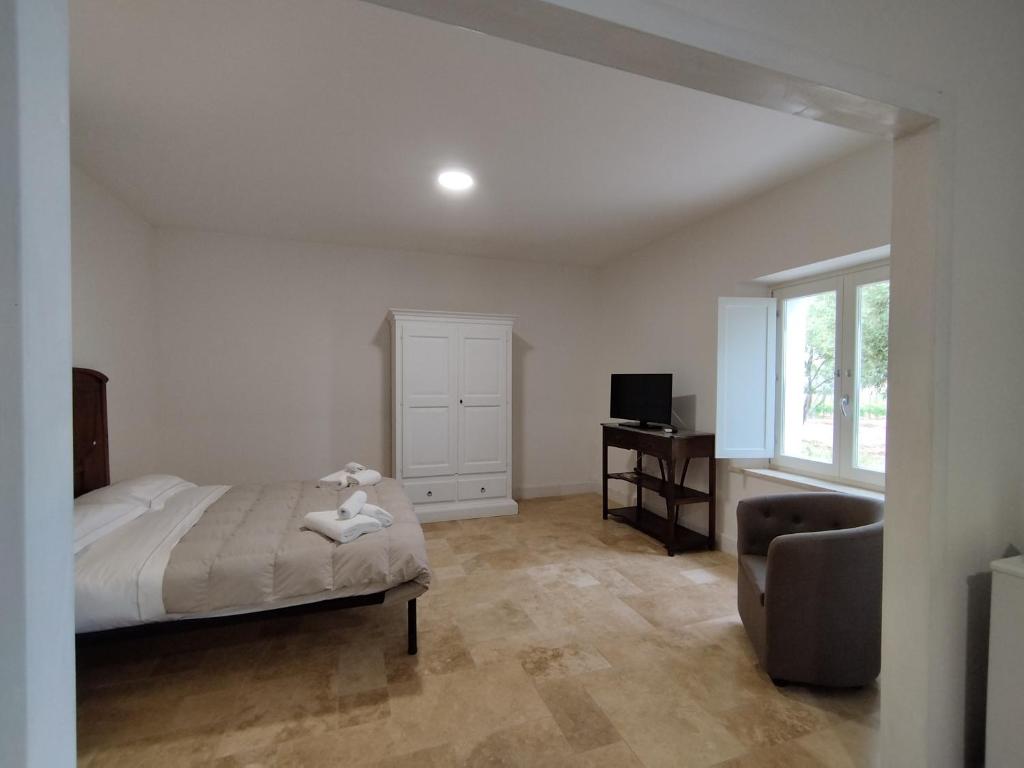 SUITE Rooms in Tenuta Asinara Vineyard في سورسو: غرفة نوم بسرير وكرسي ونافذة