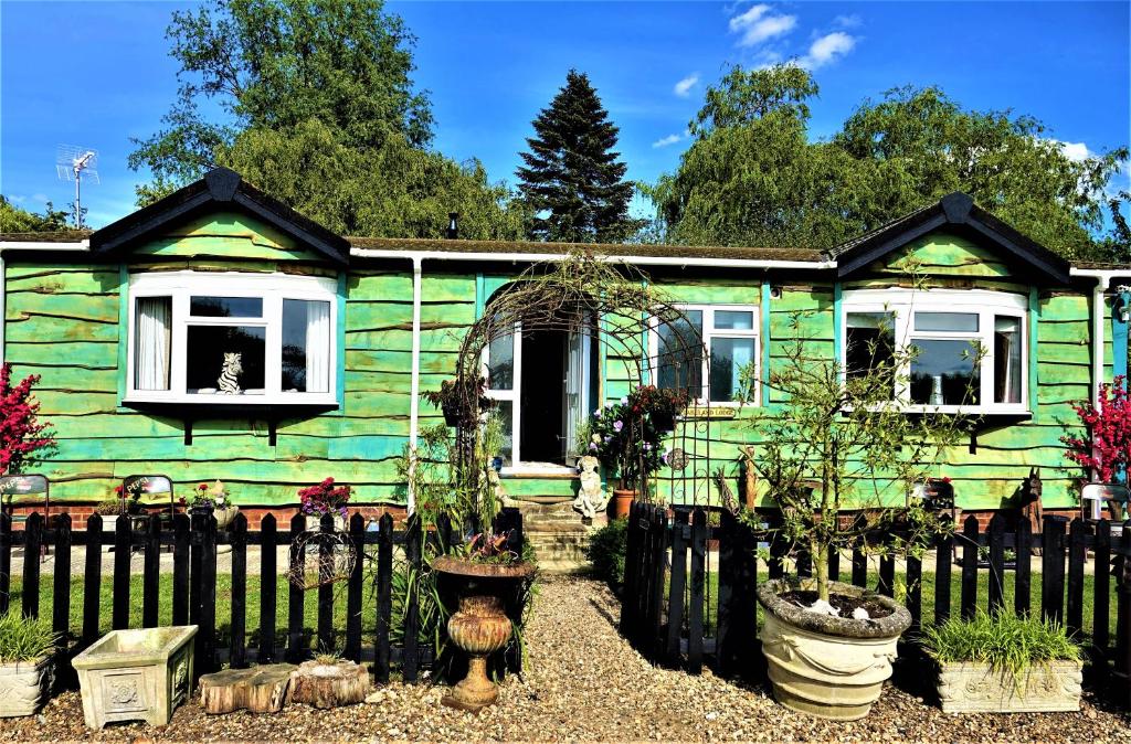 una casa verde con una valla delante en Lakeland Lodge with private Hot Tub and fishing, en Hatfield Peverel