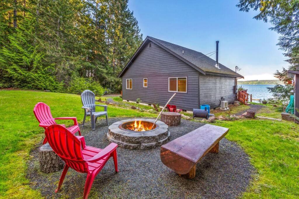 a backyard with chairs and a fire pit and a house at Seal Rock Cottage in Brinnon