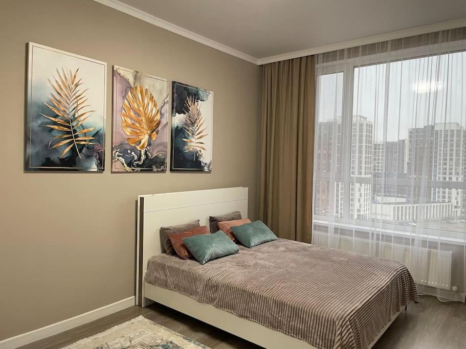 a bedroom with a bed with three paintings on the wall at Sat City Comfort in Astana