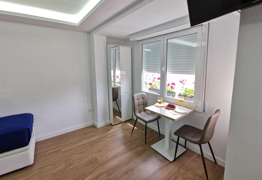 a living room with a table and chairs and two windows at Ático en Calella a 7 minutos de la playa in Calella