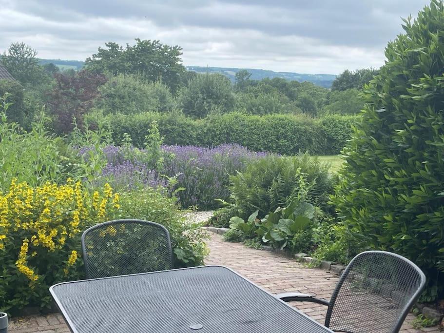 a table and chairs sitting in front of a garden at Adembenemende plek in het heuvelland-De Verrekijker in Vijlen
