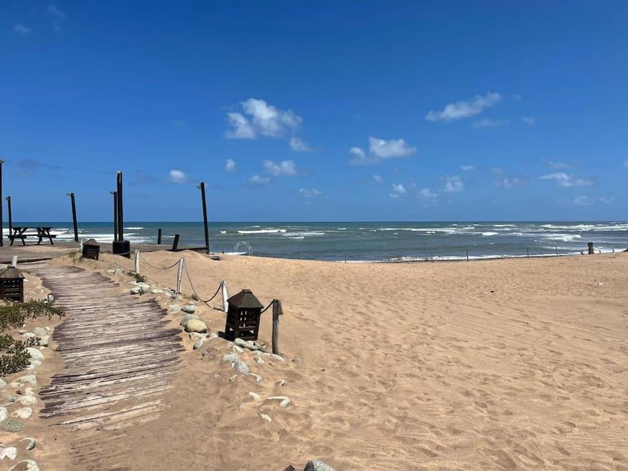 una playa de arena con un camino de madera hacia el océano en La alcazaba, résidence pieds dans l’eau à Sidi Rahal en Dar Mohammed Ould Haj Jilali