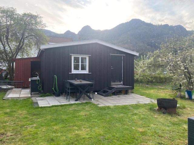 a black shed with a picnic table in a yard at Løkka,Summer cabin! in Åna-Sira