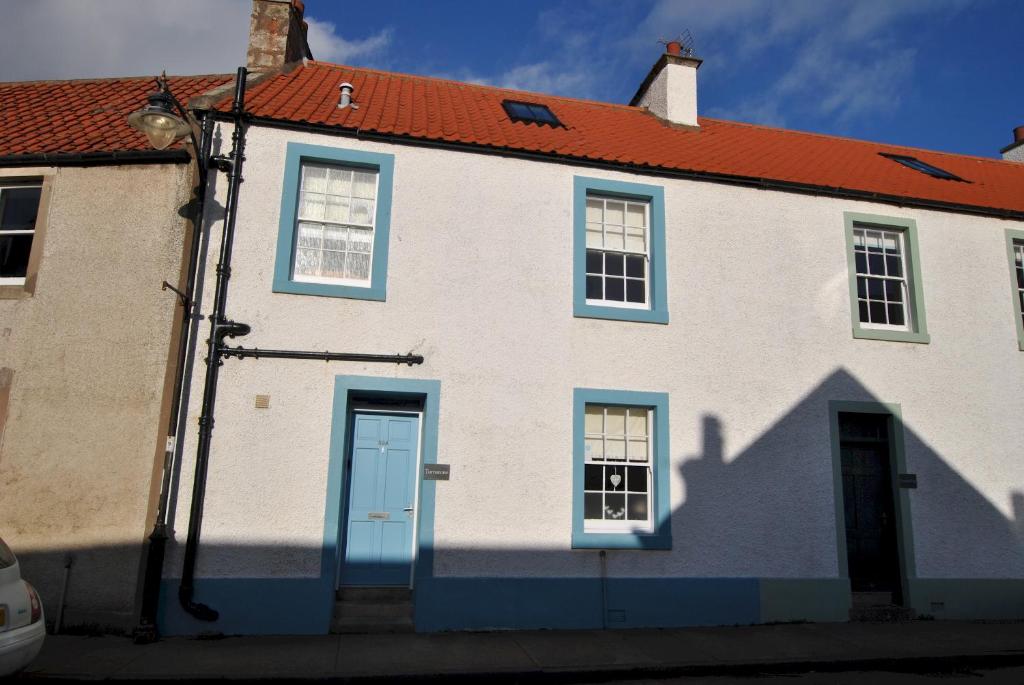 um edifício branco com janelas azuis e um telhado vermelho em Turnstone- beautiful coastal home Pittenweem em Pittenweem