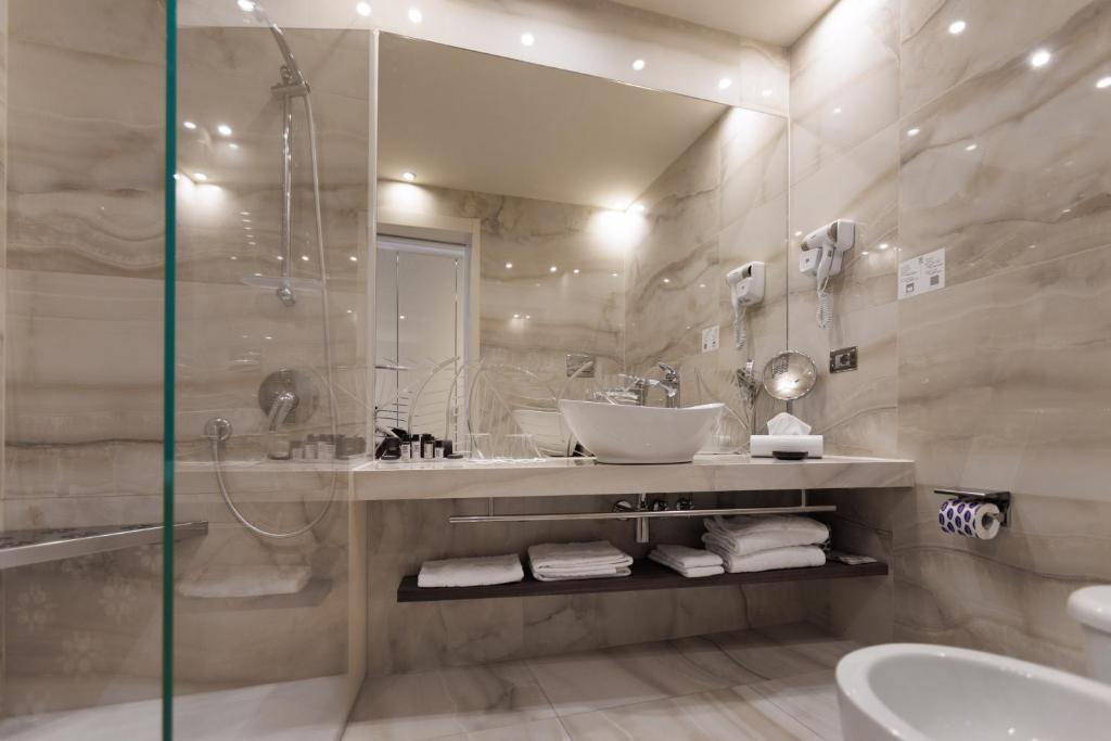 a bathroom with a sink and a mirror and a tub at Park Hotel Imperial in Limone sul Garda