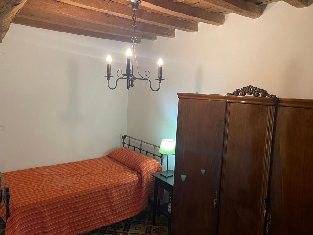 a bedroom with a bed and a cabinet and a chandelier at Casa rural Aloha Vera in Jarandilla de la Vera