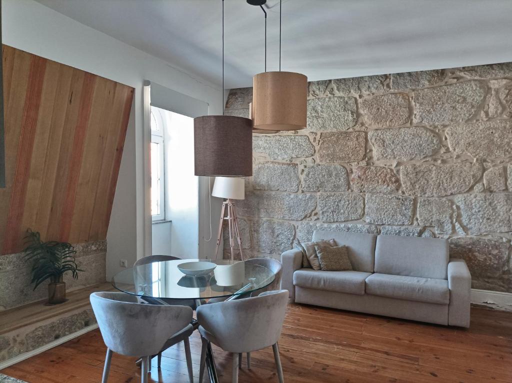 ein Wohnzimmer mit einem Glastisch und einer Steinmauer in der Unterkunft Citybreak-apartments Bolhao in Porto