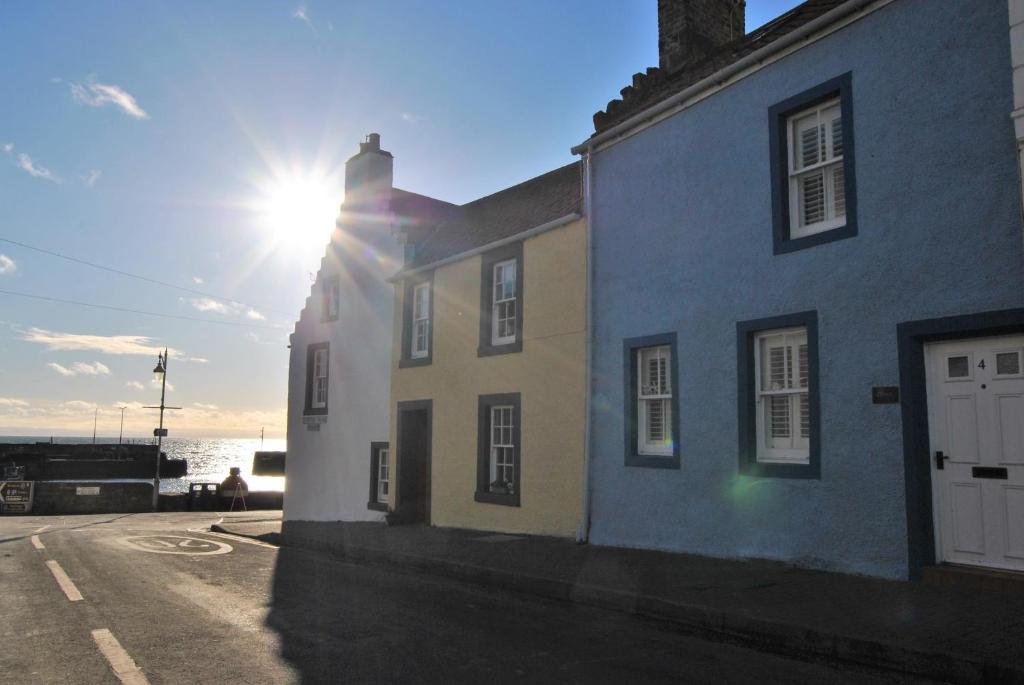 a building with the sun shining behind it at Oyster Cottage- relaxing retreat by the sea in Saint Monance
