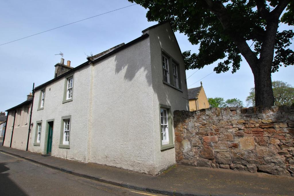 a white building next to a stone wall at Dolphin Cottage- traditional cottage on Fife Coast in Anstruther