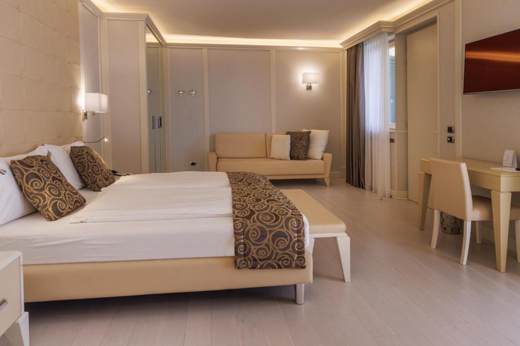 a bedroom with a bed and a couch and a table at Park Hotel Imperial in Limone sul Garda